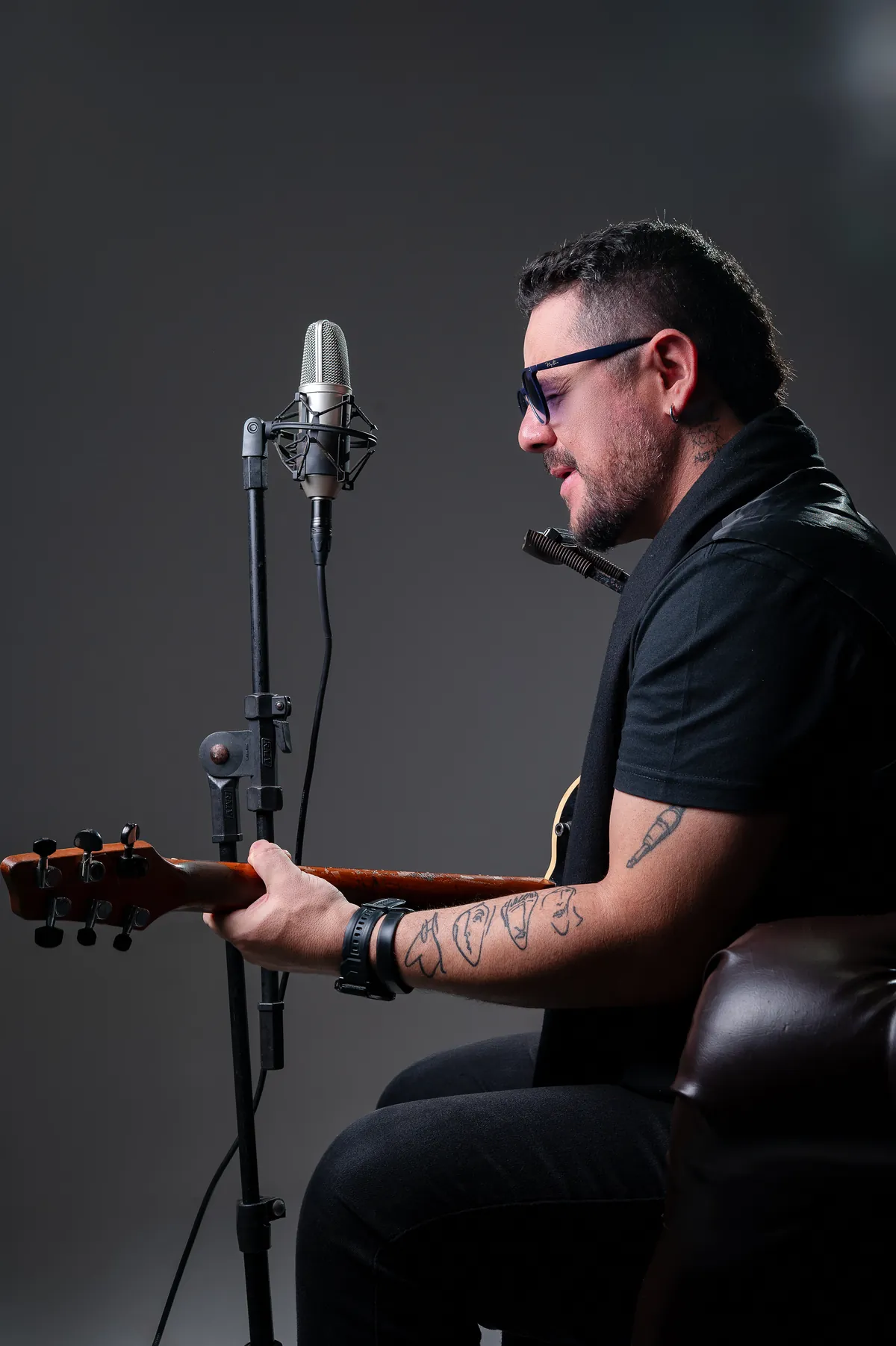 Roy sentado no estúdio tocando guitarra diante do microfone