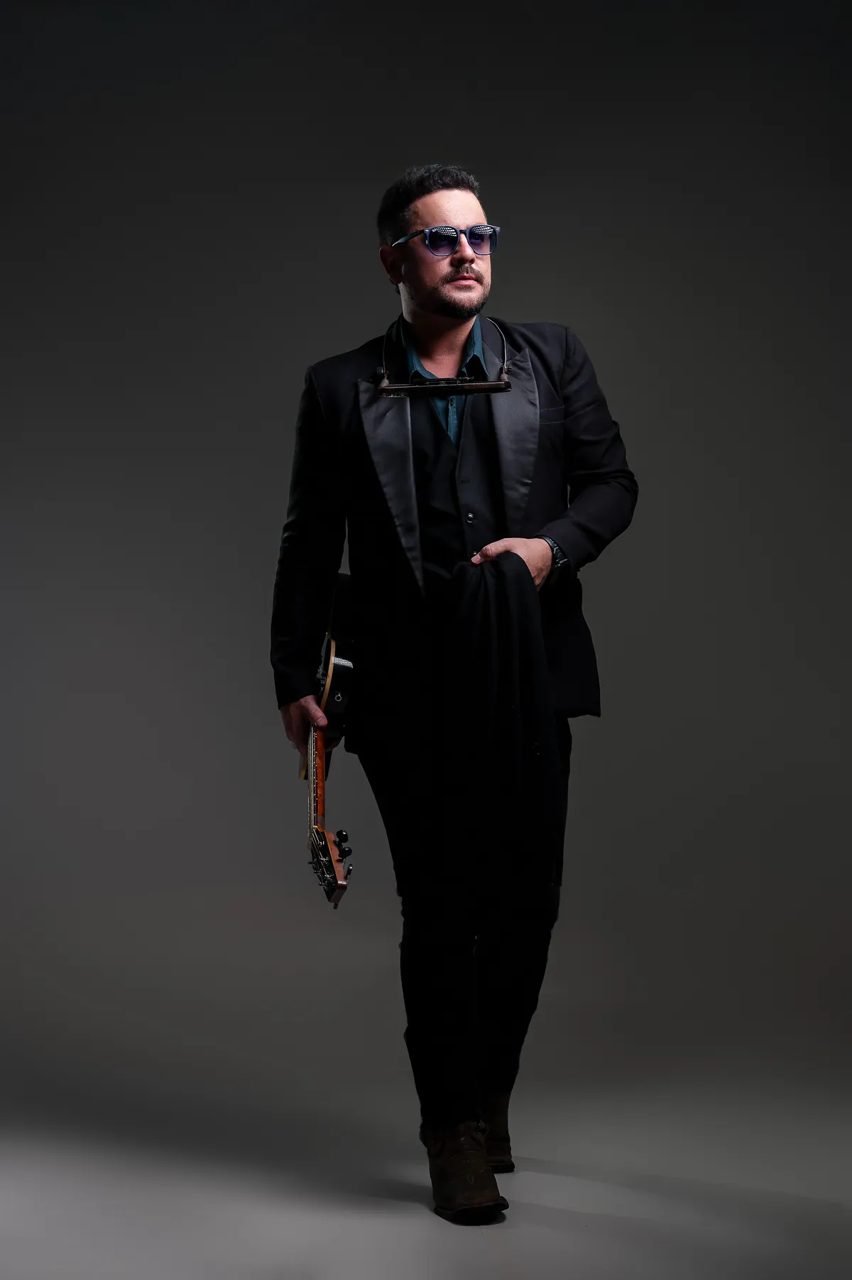 Roy de terno preto caminhando com a guitarra na mão